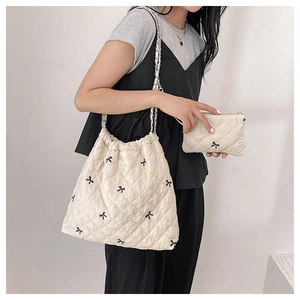 Quilted cream shoulder bag featuring black bow patterns and chain strap detail