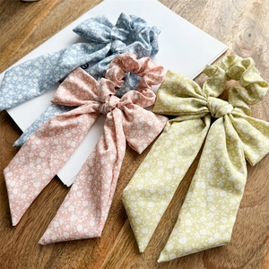 Detailed view of blue, pink and yellow floral bow scrunchies on a wooden table