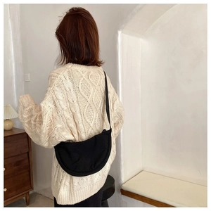 Detailed view of black nylon crescent bag worn crossbody showing texture and adjustable strap