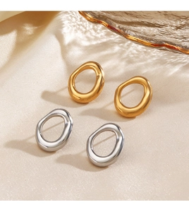Detail of irregular oval metal earrings in gold and silver finish on silk fabric