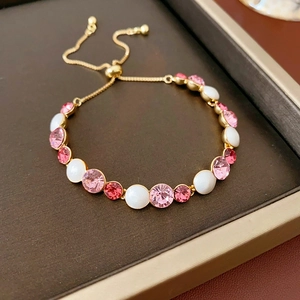 Gros plan du bracelet doré ajustable avec cristaux roses dégradés et perles blanches