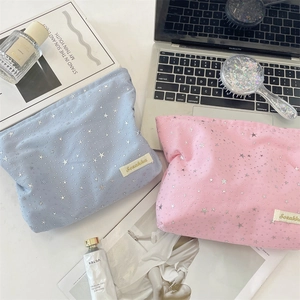 Close-up of star-patterned makeup bags in sky blue and pink on a lifestyle desk