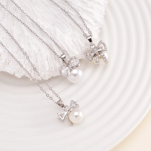 Elegant bow pearl necklace with silver accents and zircon inlay on a white textured background