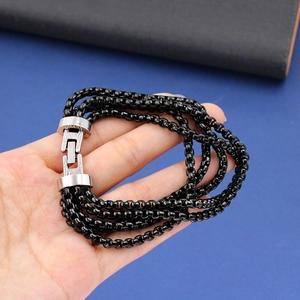Detailed close-up of a multi-layer black chain bracelet with a silver metal buckle