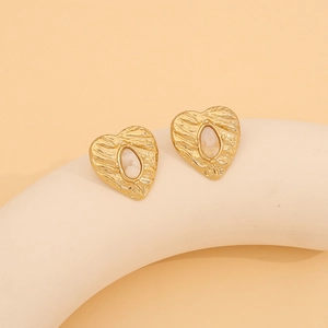 Detail of vintage gold heart earrings with cream oval inlay on minimalist plaster base