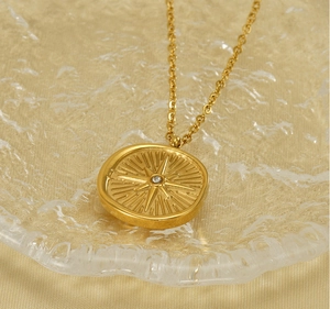 Macro view of gold north star pendant with diamond on water rippled glass tray
