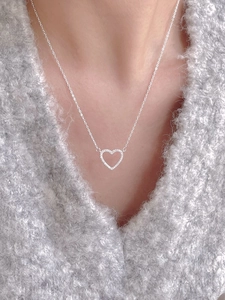 Detailed view of a silver heart pendant necklace with shimmering zircon inlay on a model