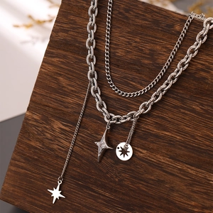 Detail view of double-layered silver alloy necklace with star pendants on wooden stand