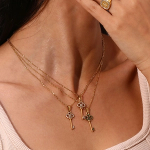 Detail view of gold key pendants with intricate hollow designs and sparkling zircon inlay