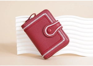 Close-up of red leather wallet featuring white contrast stitching and snap button detail