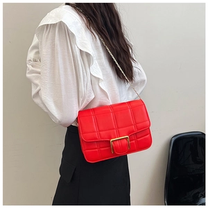 Close-up of red quilted shoulder bag featuring gold buckle and metal chain strap
