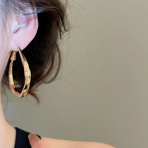 Close-up of elegant gold twisted hoop earring on model with a polished metallic finish