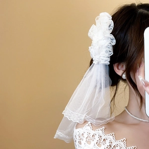 Detailed view of elegant white lace flower veil hair clip with sheer layered mesh fabric