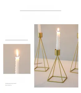 Close-up of elegant gold pyramid metal candle holder with white spiral candles