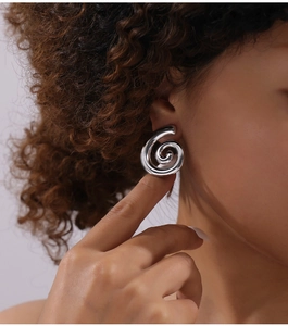 Gros plan d'une boucle d'oreille spirale argentée avec finition miroir sur le modèle