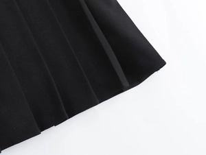 Macro shot of black pleated skirt detailing thick fabric texture and sharp pleats
