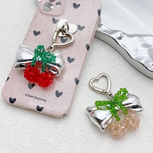 Handmade crystal cherry bow keychain with silver heart clasp on a stylish phone case