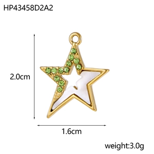 Macro view of a 2cm gold star pendant with green rhinestones and white shell inlay