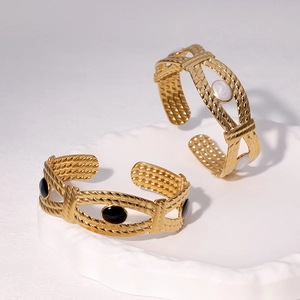 Détail de bracelets joncs vintage en acier titane doré avec incrustations noir et blanc