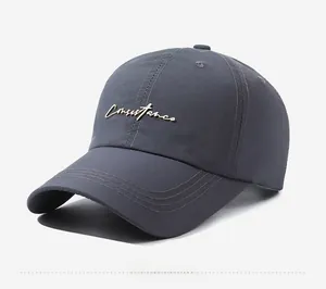 Detail view of charcoal grey baseball cap with golden Consistance metallic lettering