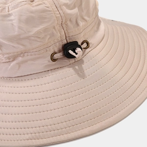 Close-up of beige outdoor hat with adjustable drawstring, metal eyelets and reinforced stitching