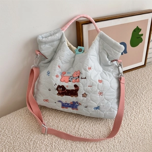 Close-up of light blue quilted crossbody bag with cute cat embroidery and luck lettering