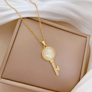 Detail of gold key necklace with white mother of pearl inlay and crystal accents