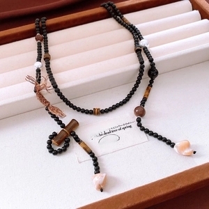 Detail of beaded long necklace with tiger eye stone and tassel on a jewelry display tray