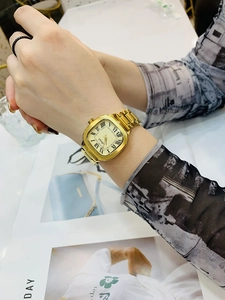 Close-up of golden square watch with Roman numerals and metal strap on woman wrist