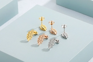 Three pairs of leaf-shaped stud earrings in gold, rose gold, and silver finishes