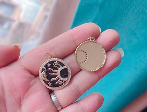 Detailed view of a gold pendant featuring celestial sun, moon, and stars with rhinestones