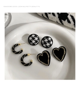 Detailed set of retro checkered and heart-shaped earrings on a ceramic display