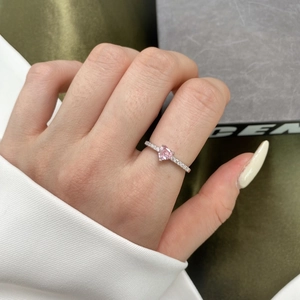 Gros plan d'une bague en argent S925 avec zircon rose en forme de cœur portée au doigt