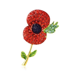 Close-up of red poppy flower brooch with sparkling rhinestones on golden alloy base