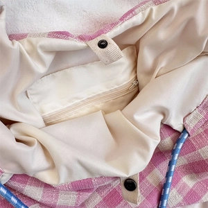 Close-up of checkered tote bag interior with zipper pocket and blue drawstring closure