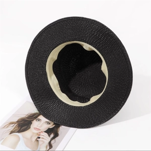 Détail d'un chapeau en paille noire montrant la bande de confort et le tissage précis