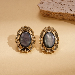 Close-up of vintage baroque style earrings with dark oval resin and gold-tone metal frame