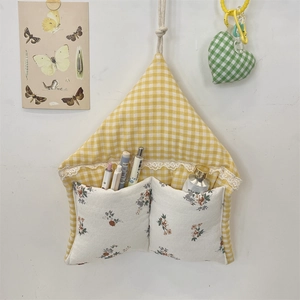 Detail of wall hanging storage bag with yellow checkered fabric and floral lace pockets