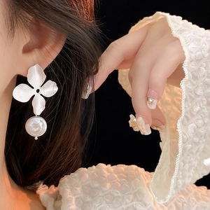 Detailed close-up of a brushed silver flower earring with a white baroque pearl drop