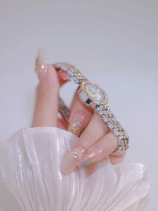 Close-up of a luxury two-tone women's watch with a diamond bezel on a model's wrist