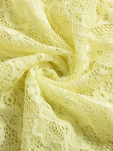 Gros plan sur un tissu de dentelle jaune pâle aux motifs floraux et texture en maille