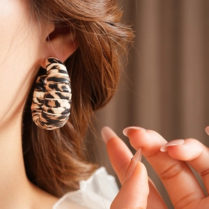 Close-up of leopard print C-shaped earrings worn by a model with a retro aesthetic