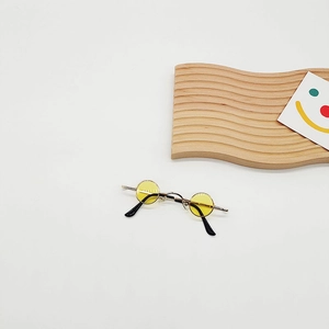 Close-up of mini round gold metal sunglasses with yellow lenses for pets or dolls