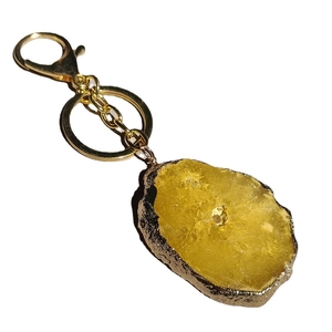 Natural yellow crystal geode keychain with gold plated irregular stone pendant on white background