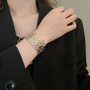 Detail showing gold hollow geometric wide cuff bracelet on a model wearing black