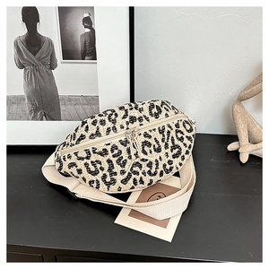 Detail view of woven leopard print fanny pack with straw texture and beige strap