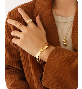 Detail of 18K gold plated bangle and bear pendant necklace on brown corduroy blazer