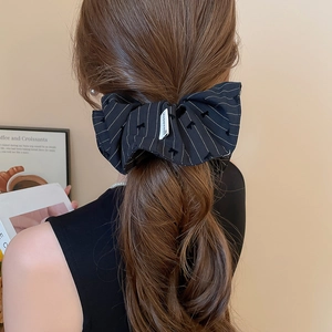 Détail d'un chouchou à nœud rayé avec étiquette Happiness et broderie élégante