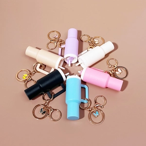 Mini tumbler cup keychains in seven pastel colors arranged in a circle on plain background