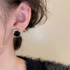 Gros plan d'élégantes boucles d'oreilles noires rondes avec une auréole de cristaux